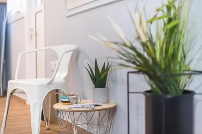 a white chair sitting next to a table with plants at City Nest Apartment by Cloudkeys in Athens