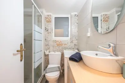a bathroom with a sink and a toilet and a mirror at City Nest Apartment by Cloudkeys in Athens