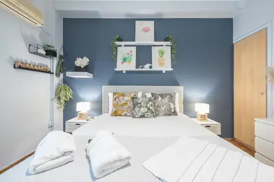 a bedroom with a white bed and blue walls at City Nest Apartment by Cloudkeys in Athens