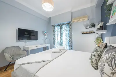 a bedroom with a bed and a chair and a tv at City Nest Apartment by Cloudkeys in Athens