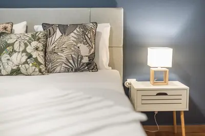 a bedroom with a bed and a nightstand with a lamp at City Nest Apartment by Cloudkeys in Athens