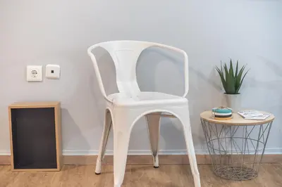 a white chair sitting in a room next to a table at City Nest Apartment by Cloudkeys in Athens