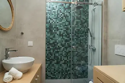 a bathroom with a glass shower with a sink at Luxury apartment in Alimos in Athens