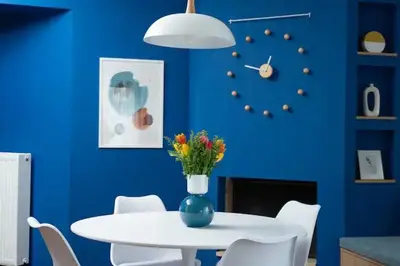 a blue dining room with a white table and a vase with flowers at Luxury apartment in Alimos in Athens