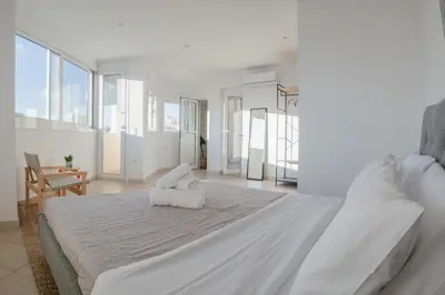 a white bedroom with a large bed with white sheets at Casa Acropolis - Stunning 3Br Apt with Private Terrace in Athens