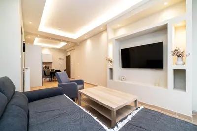 a living room with a couch and a tv on a wall at Filoxenia MG Projects Acropolis Dimitrakopulou in Athens