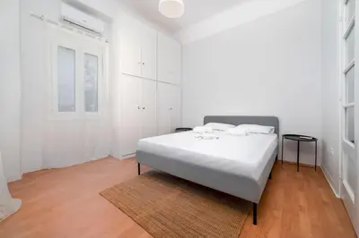 a white bedroom with a white bed and a wooden floor at Thissio Getaway 2BA next to Athens ancient market in Athens