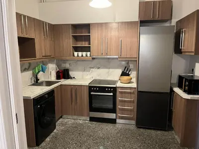 a kitchen with wooden cabinets and a black refrigerator at Delightful 2BR Apt in the Heart of Kypseli! in Athens