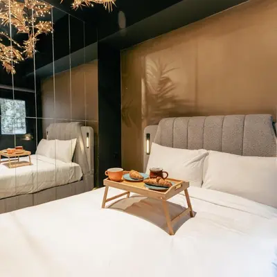 a bedroom with two beds and a table on a bed at Black & Gold Tsakalof 17 by Zeussuites in Athens