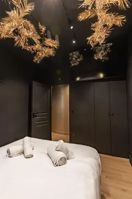 a bedroom with two towels on a bed with chandeliers at Black & Gold Tsakalof 17 by Zeussuites in Athens