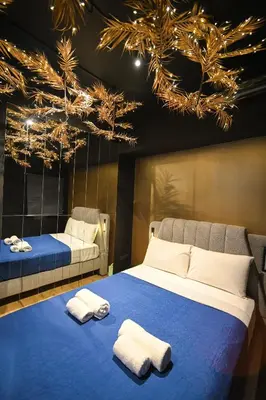 a bedroom with two beds with towels and lights at Black & Gold Tsakalof 17 by Zeussuites in Athens