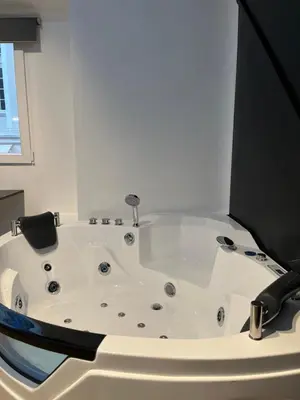 a bath tub in a room with a window at Platinum Jacuzzi Tsakalof 17 by Zeussuites in Athens