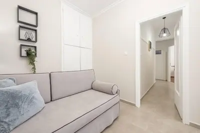 a white living room with a couch and a hallway at Athens city gem in koukaki in Athens