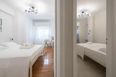 a white bedroom with two beds and a dining room at Athens city gem in koukaki in Athens