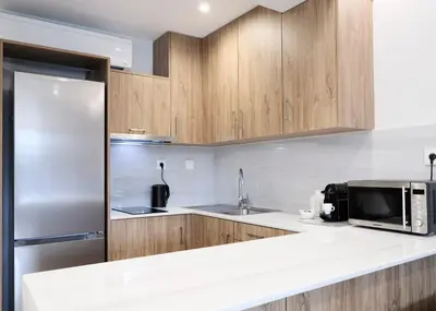 a kitchen with wooden cabinets and a stainless steel refrigerator at Bright space with street view, near Acropolis in Athens