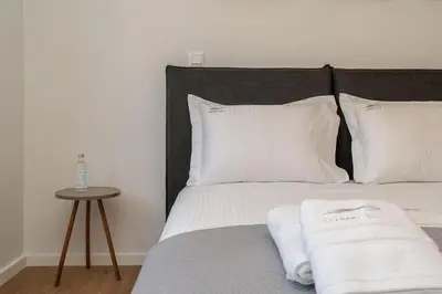 a bed with white sheets and pillows and a table at Kypseli Elegant Living in Athens
