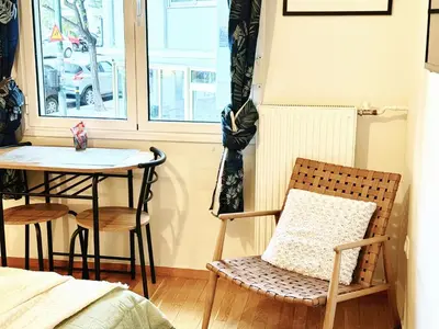 a chair and a table in a room with a window at Cozy Aparthotel Pangrati in Athens