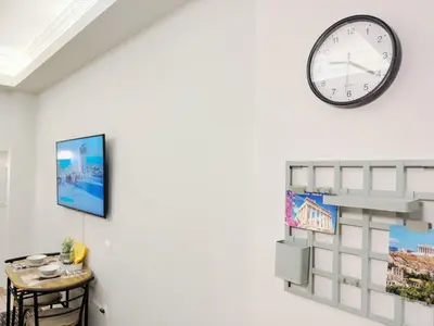 a clock hanging on a wall next to a table at Cozy Aparthotel Pangrati in Athens