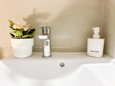 a bathroom sink with a bottle of soap and a flower at Cozy Aparthotel Pangrati in Athens