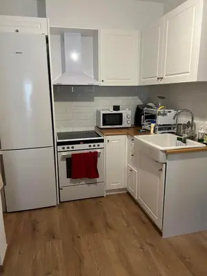 a kitchen with white cabinets and a white refrigerator at Zen Alimos in Athens