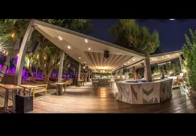 a covered deck with tables and chairs at night at Zen Alimos in Athens
