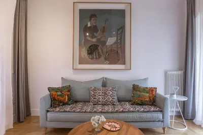 a living room with a couch and a picture of a guitarist at Timeless Athens Cozy Apartment in Athens