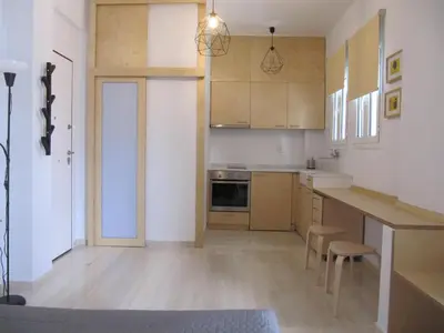 a kitchen with white cabinets and a table and chairs at Cosy Studio at the heart of glyfada in Athens