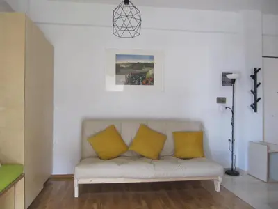 a white living room with a couch with yellow pillows at Cosy Studio at the heart of glyfada in Athens