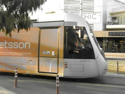 an orange and white train on a city street at Cosy Studio at the heart of glyfada in Athens