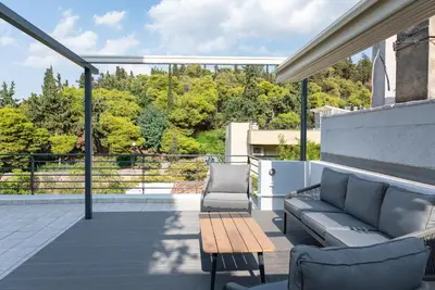 a patio with a couch and a table and chairs at Ideal Maisonette next to Kallimarmaro Stadium in Athens