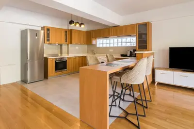 a kitchen with wooden cabinets and a island with bar stools at Ideal Maisonette next to Kallimarmaro Stadium in Athens