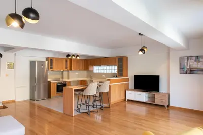 a kitchen with wooden cabinets and a table with stools at Ideal Maisonette next to Kallimarmaro Stadium in Athens