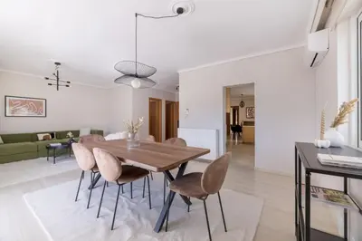 a dining room and living room with a wooden table and chairs at Comfortable 3BR Family Residence in Agia Paraskevi by UPSTREET in Athens
