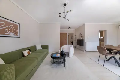 a living room with a green couch and a table at Comfortable 3BR Family Residence in Agia Paraskevi by UPSTREET in Athens