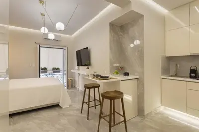 a bedroom with a bed and a kitchen with stools at Elegant minimal studio in Kerameikos in Athens