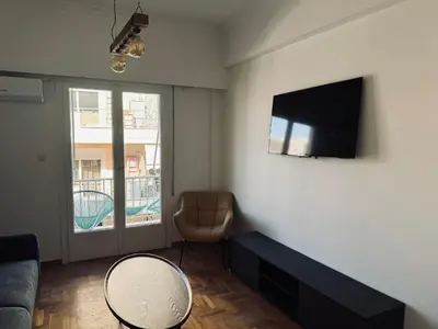 a living room with a couch and a tv on a wall at Athens Koukaki Apartment in Athens