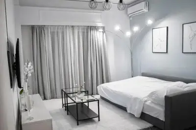 a white bedroom with a bed and a table at Luxury Apartment near Acropolis in the Heart of Athens in Athens