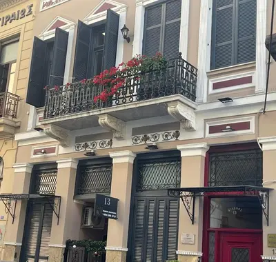 a building with a balcony with red flowers on it at Near to the Port in Piraeus