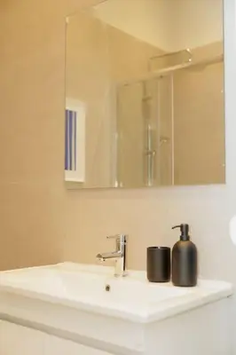 a bathroom sink with a mirror and a soap dispenser on it at Modern 2BDR apartment in Pagrati in Athens