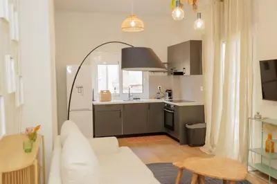 a living room with a white couch and a kitchen at Modern 2BDR apartment in Pagrati in Athens