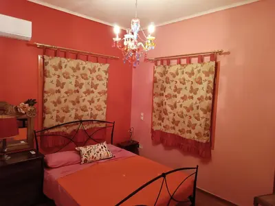 a bedroom with a bed with red walls and a chandelier at Eleni's Astrous Home in Athens