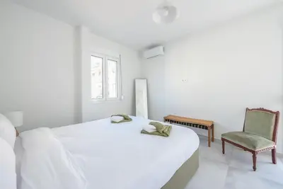 a white bedroom with a bed and a chair at Zen Top, Exarchia in Athens