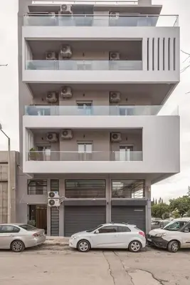 two cars parked in front of a tall building at Modern & Spacious Αpartment in Athens