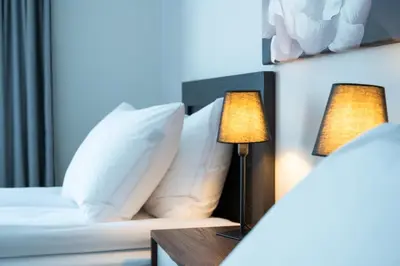 a bed with white pillows and a table with a lamp at Medluxe SMART APARTMENT! in Athens
