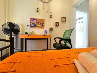 a bedroom with a desk and a bed with an orange blanket at Dolce Casa an athenian residence with private garden in Athens