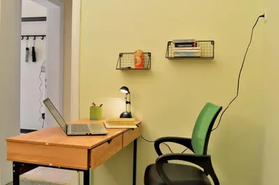 a desk with a laptop and a chair in a room at Dolce Casa an athenian residence with private garden in Athens