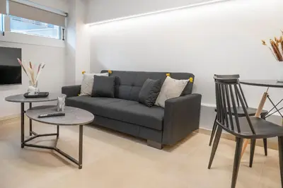 a living room with a couch and two tables and chairs at Oculus Kolonos Suites by Live&Travel in Athens
