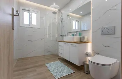 a white bathroom with a toilet and a sink at Athens Hill Suite 2 in Athens