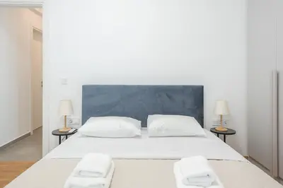 a white bedroom with a large white bed with two lamps at City Vibes Stylish 2BR and a Stunning Balcony in Athens