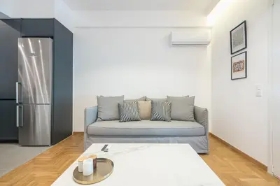 a living room with a couch and a refrigerator at City Vibes Stylish 2BR and a Stunning Balcony in Athens